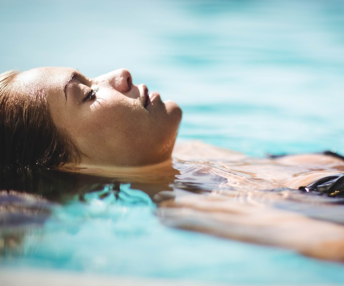 Peaceful blonde floating in the pool with eyes closed